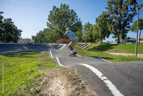 A young Black man riding a skateboard at a pump track