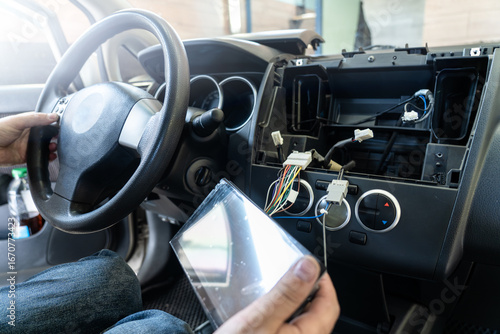 Repairman replacing car multimedia unit and working with dashboard wiring, vehicle electronics upgrade, automotive repair.