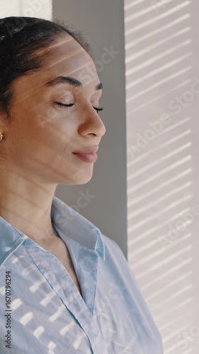 Confident young African American businesswoman taking deep breath, looking through the office window