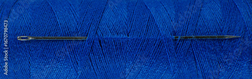 Close up view of a needle and blue thread for sewing