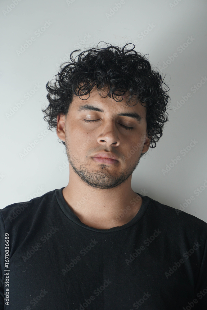 Obraz premium Latino boy with curly hair on a white background and a black t-shirt
