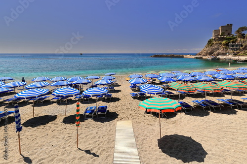 Fototapeta Naklejka Na Ścianę i Meble -  Aurora Tower on San Cristoforo hill overlooking the striped umbrellas covering the old town -paese antico- beach W end. Monterosso al Mare-Liguria-247