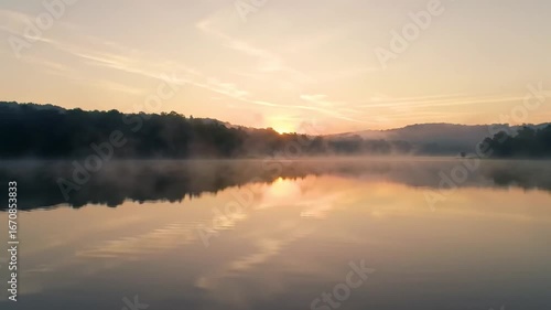 Wallpaper Mural Still lake reflecting a sunrise surrounded by misty trees  hills Sky shows light clouds Torontodigital.ca