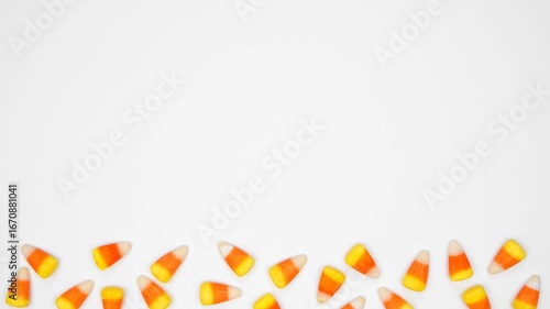 Halloween candy corn bottom border. Top down view stop motion loop video over a white background with copy space.