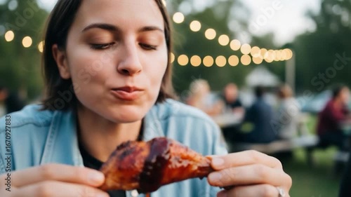 Woman Enjoying BBQ Chicken Wing Outdoors at Evening.