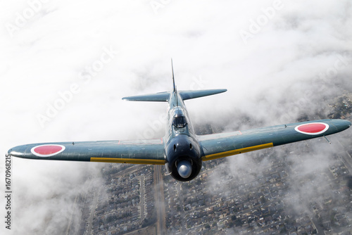 Obraz na plátně Frontal view of a A6M Zero (WWII Japanese fighter plane) flying over clouds in
