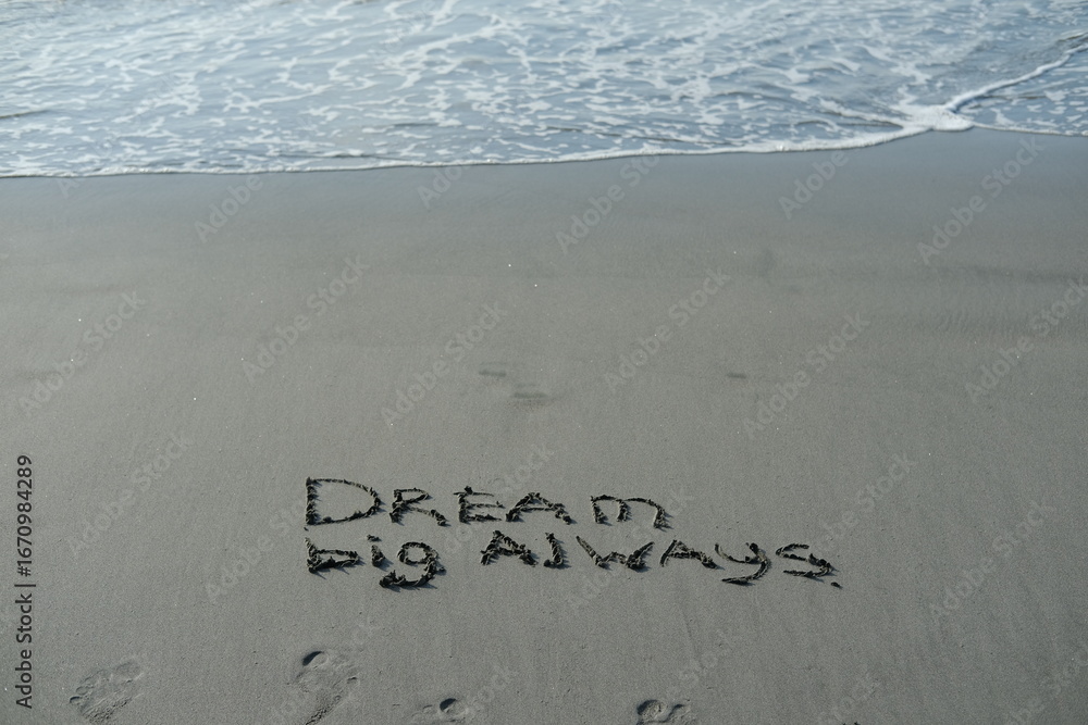Fototapeta premium Dream big always written in sand in sunlight