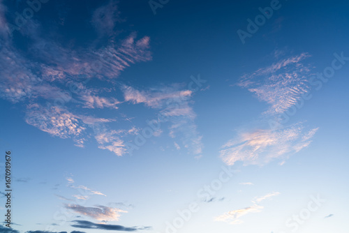 A serene twilight scene over a calm lake with distant hills and a glowing hor...