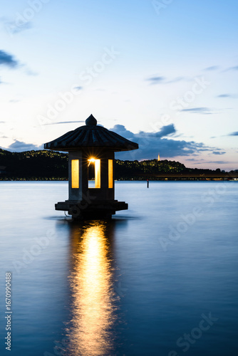 Silhouetted traditional lanterns on West Lake at dusk in Hangzhou, China, wit...
