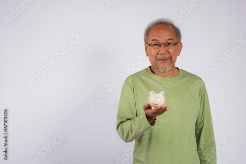 фотографія Portrait smiling Asian older man holding white piggy bank on hand studio shot is