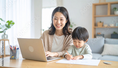明るい自宅リビングでノートパソコンを使う笑顔の母親と、隣で絵を描く子どもの姿が伝える在宅勤務と子育ての両立シーン
