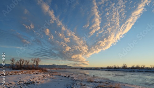 Winter landscape with dramatic clouds at sunset over a river