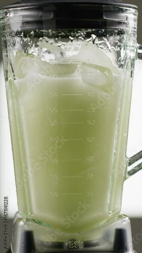 View of a blender with a frozen green liquid inside creating a refreshing and icy beverage