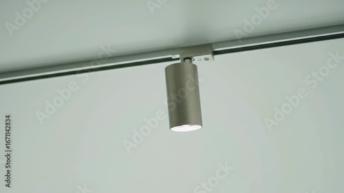 A silver track lighting fixture with a spotlight on a white ceiling is shown close up