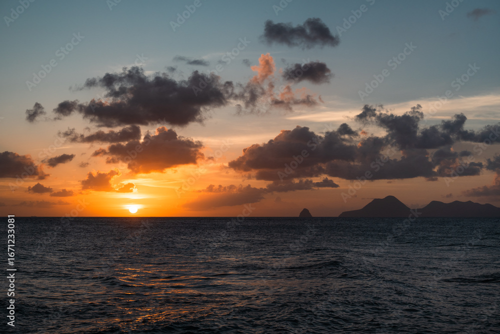 Naklejka premium Breathtaking sunset over the ocean showcasing vibrant colors and tranquility.