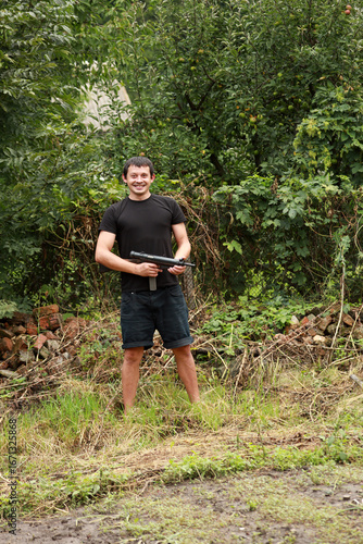 A criminal in black shirt with submachine gun in hands standing in the park