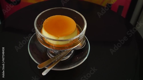  Caramel custard pudding in glass cup on black table, Handheld shot