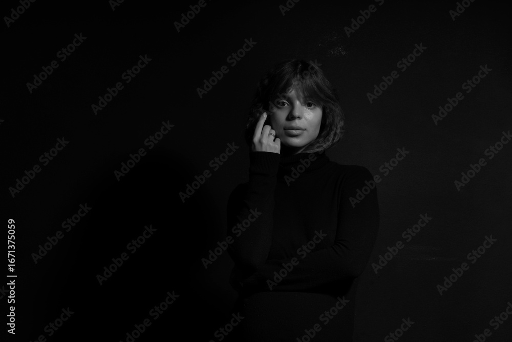 Obraz premium Low key black and white portrait of young woman in black sweater
