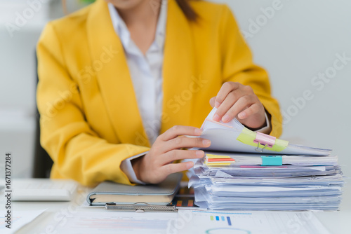 Focused Analysis: A person carefully reviews a stack of important documents at the office desk. Capturing a moment of meticulous attention to detail.