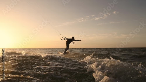 Dynamic kitesurfer riding powerful wave in slow motion during golden hour sunset showing extreme water sport adrenaline strength energy movement and breathtaking athletic outdoor lifestyle