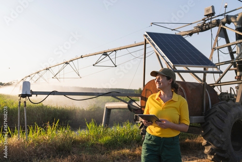 Farmer using digital tablet with solar powered irrigation system outdoors