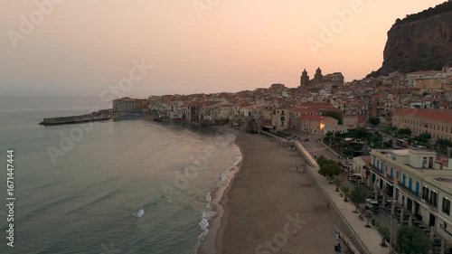 Aerial Drone Shot Flying Over The Coastal Town Of Cefalu And Beach In Sicily, Italy At Sunrise.
