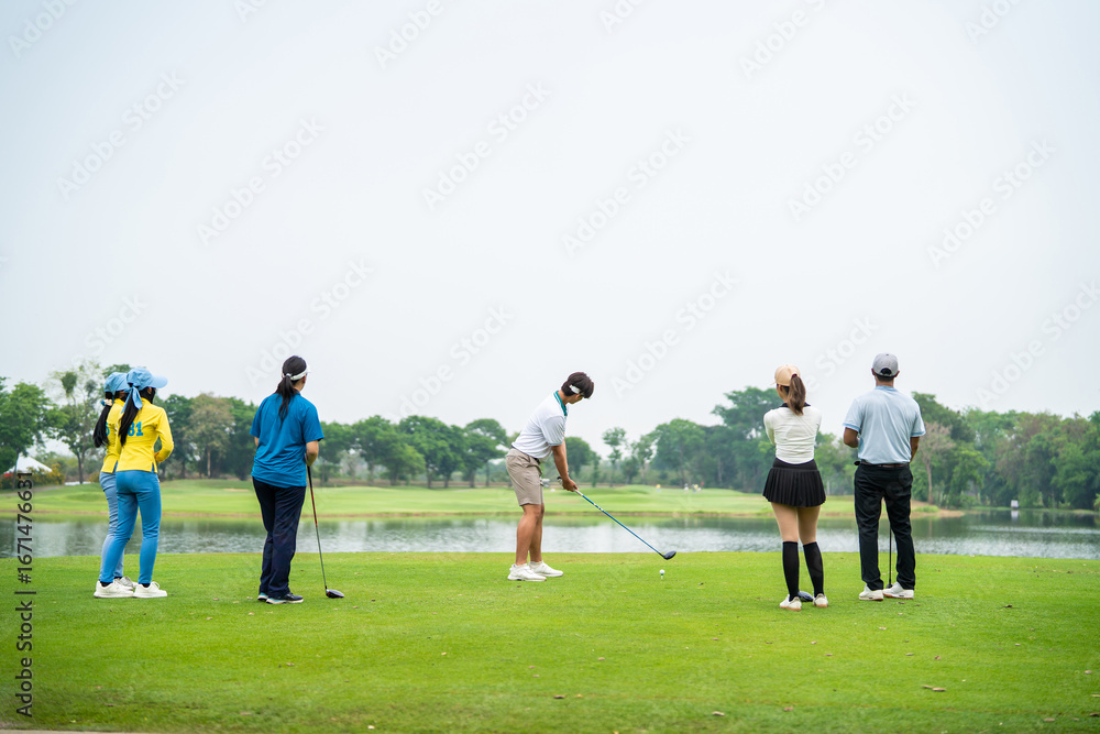 Obraz premium Group of young pro golfers swings their club on scenic golf course.