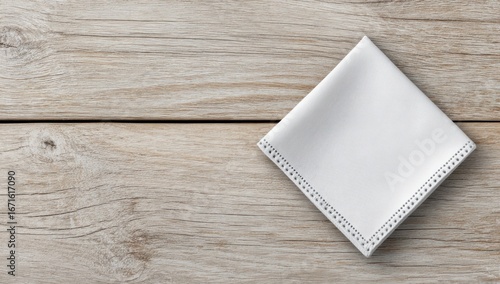 Neat white napkin, diagonally folded, rests on rustic wood planks, casting a faint shadow