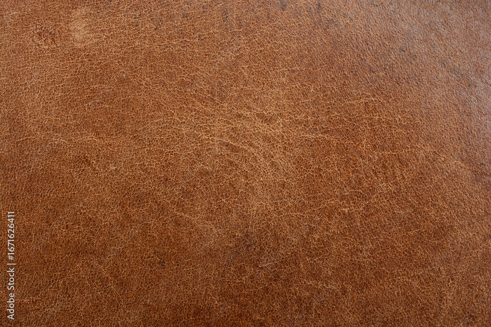 Fototapeta premium A close-up, full-frame shot of a rich brown distressed leather surface, showcasing its aged and rustic texture