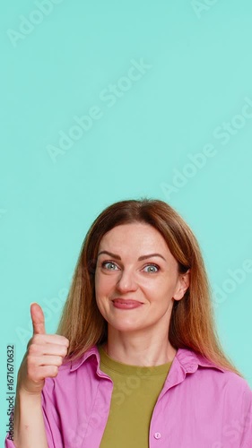 Wallpaper Mural Middle-aged woman points finger upward with serious face, clearly signaling importance, asking to focus attention on something above. Girl isolated on blue background shows emphasis gesture and intent Torontodigital.ca