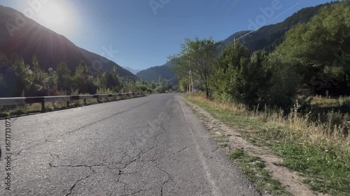 Movement along a scenic road leading into the mountains. Coniferous forests rise in the background, creating a picturesque travel scene with natural beauty, outdoor adventure, and peaceful highland la