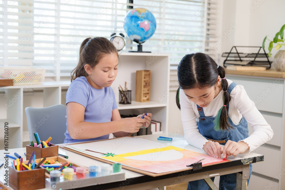 Asian elementary girl student and caucasian classmate concentrating on large artwork using crayons at classroom desk creativity imagination teamwork childhood artistic cooperative learning Asian elementary girl student and caucasian classmate concentrating on large artwork using crayons at classroom desk creativity imagination teamwork childhood artistic cooperative learning