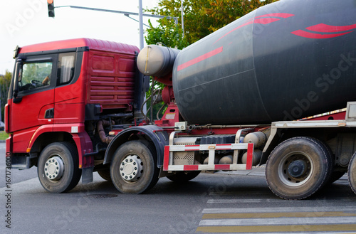 Heavy concrete truck making a turn at an intersection during the late afternoon in an urban setting