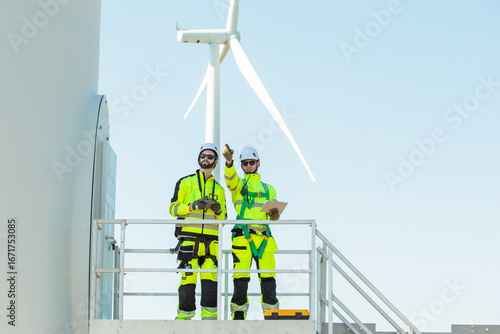 Team of engineers inspecting and planning maintenance at wind turbine power site.