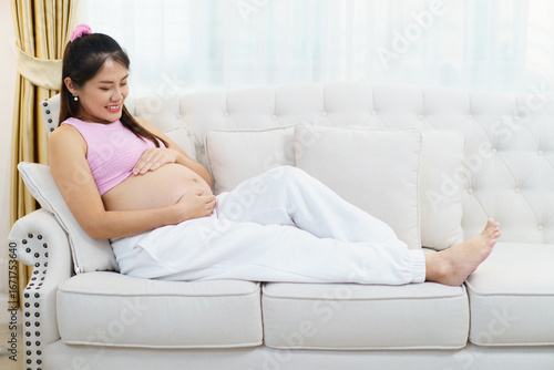 Pregnant woman 30 weeks sitting on sofa, touching belly with love. Relaxed motherhood, care, and family lifestyle at home. Free Download Pregnant woman 30 weeks sitting on sofa, touching belly with love. Relaxed motherhood, care, and family lifestyle at home. - GFXLoad