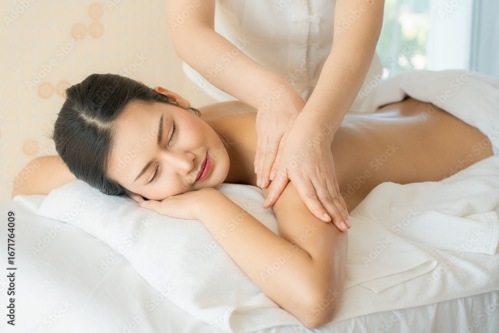 Asian woman enjoying relaxing arm massage with oil at spa, lying on white towel with peaceful smile and closed eyes, symbolizing wellness, self-care, and beauty in tranquil setting. Asian woman enjoying relaxing arm massage with oil at spa, lying on white towel with peaceful smile and closed eyes, symbolizing wellness, self-care, and beauty in tranquil setting.