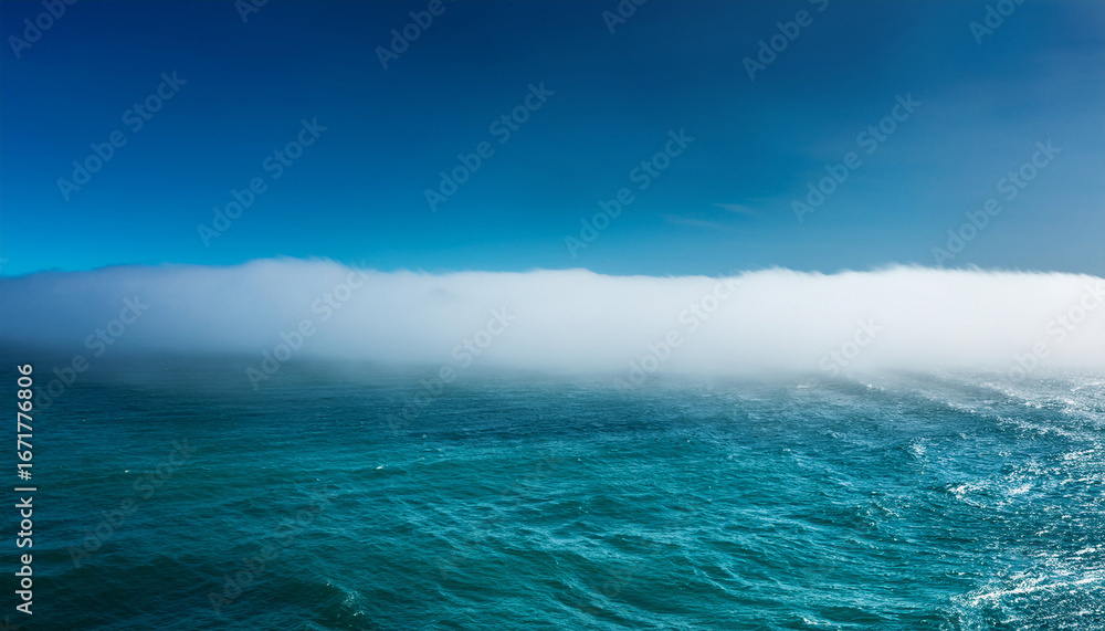 Fototapeta premium rolling white fog bank over a teal ocean horizon
