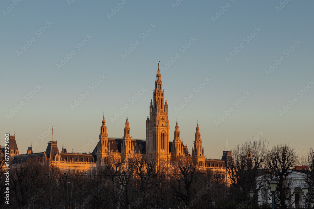 Naklejka premium Vienna, Austria 3-19-2025 The Vienna City Hall during golden hour is the town hall located at the rathausplatz in the centre of town. The Gothic Revival building was designed by Friedrich von Schmidt.