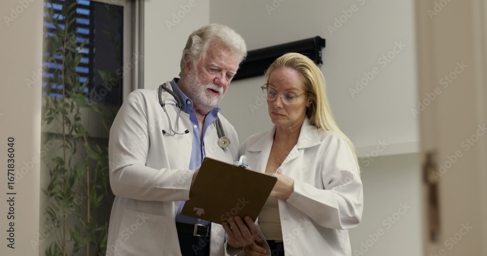 Obraz premium Healthcare Workers Standing Together in Clinical Setting While Going Over Notes and Discussing Medical Chart with Professional Focus