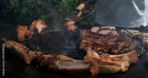grilling assorted meat on outdoor barbecue with heavy smoke rising from sizzling ribs and sausages, captured in super slow motion with a highspeed camera