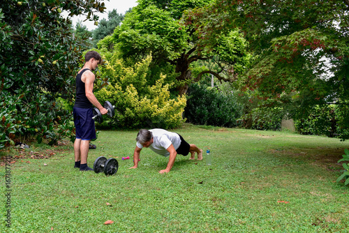 Outdoor workout session in the garden with weights and push-ups