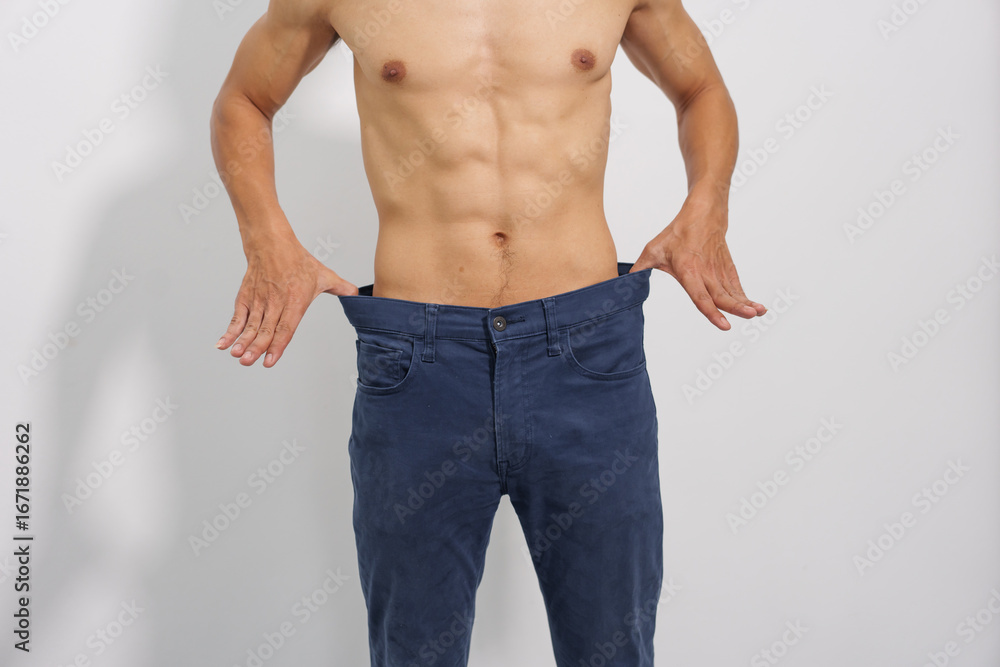 Fototapeta premium A fit man with a toned physique poses confidently in blue jeans, highlighting his healthy lifestyle and casual yet stylish look.