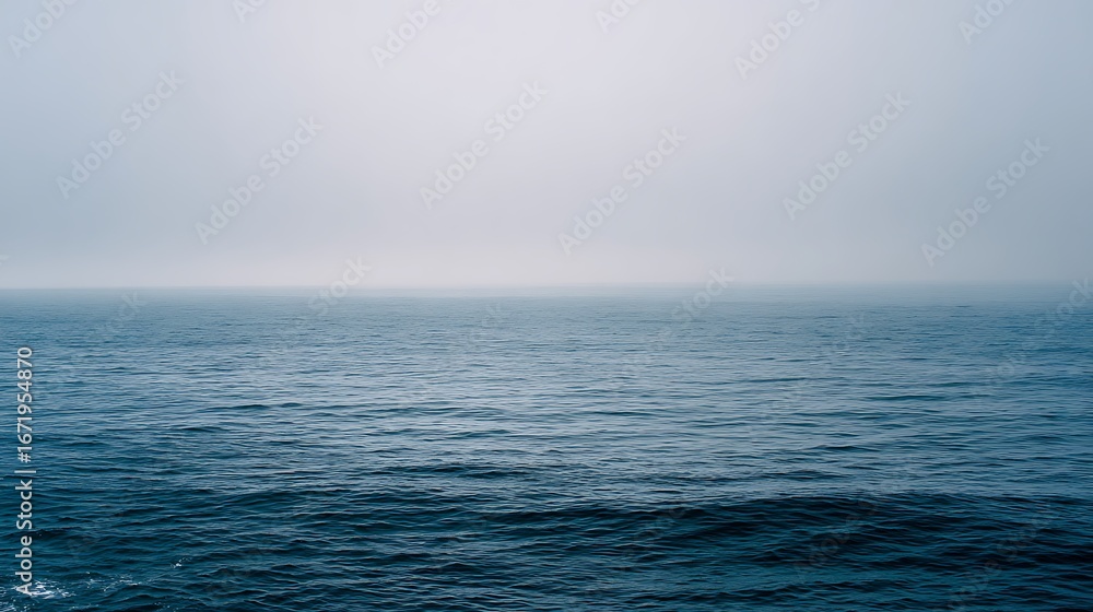 Obraz premium misty horizon over calm ocean with blue and gray water tones 
