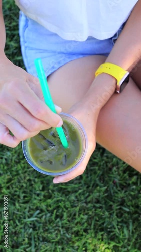 Woman holding and mixing iced matcha tea