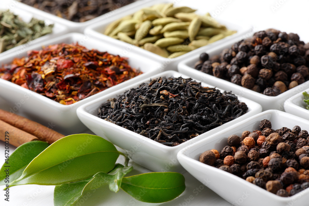 Fototapeta premium Assorted teas and spices in small white bowls with cinnamon sticks and leaves