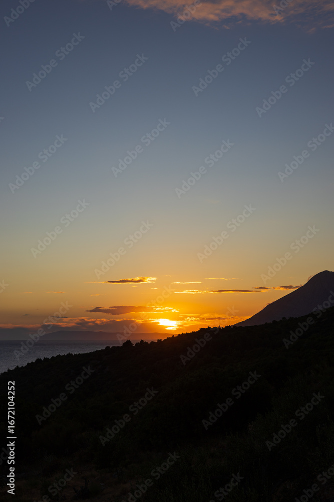 Obraz premium Sunset over the Adriatic Sea with a view of the mountain slope and the coast. Podaca village, Makarska Riviera, South Dalmatia, Croatia.