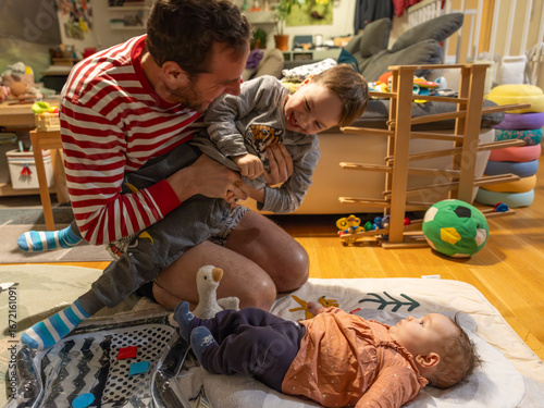 Foto Neugeborenes spielt mit Bruder und Papa