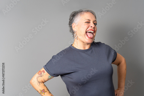 Playful senior woman sticking out tongue and winking in studio