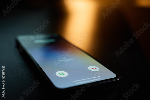 Wallpaper Mural Close-up of smartphone lying on table in dark room with incoming call on screen. Concept of communication, technology, and mobile connection Torontodigital.ca