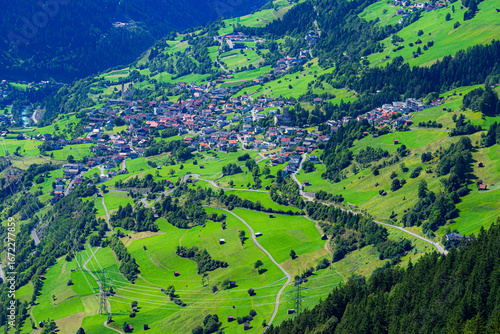 Blick hinunter auf die Stadt Fließ im Inntal, umgeben von sommerlichen, fruchtbaren Weideflächen und Waldstücken;  Österreich, tirol